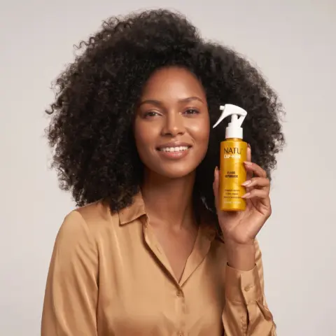 Mulher de cabelo crespo segurando o Fluido Reparador Natucap Hair