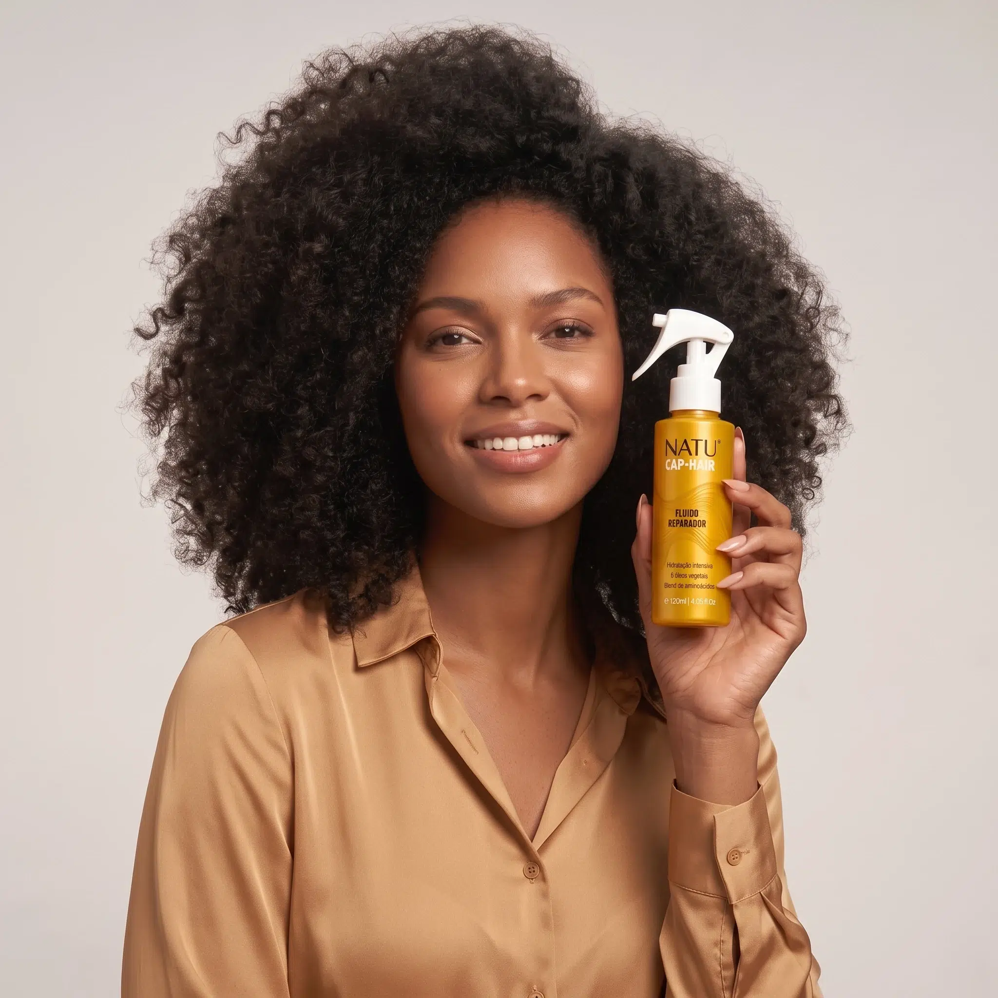 Mulher de cabelo crespo segurando o Fluido Reparador Natucap Hair